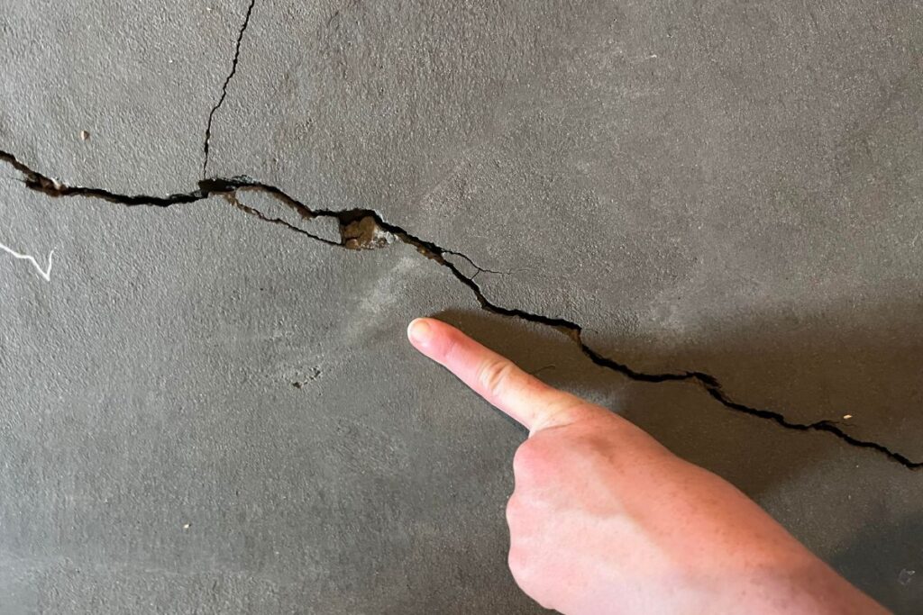 hand pointing the crack on concrete floor