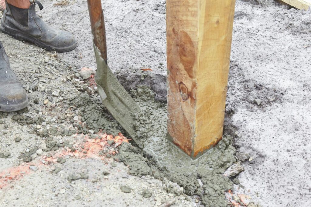 a man mixing and pouring concrete in fence post