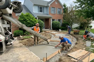 Professional concrete contractors pouring and finishing fresh concrete for a new residential walkway, with forms and a prepared gravel base surrounding the installation.